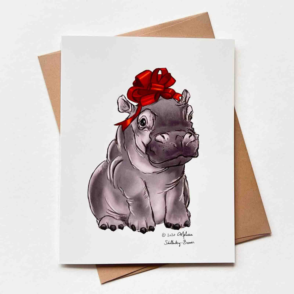 a baby hippopotamus with a red bow on its head