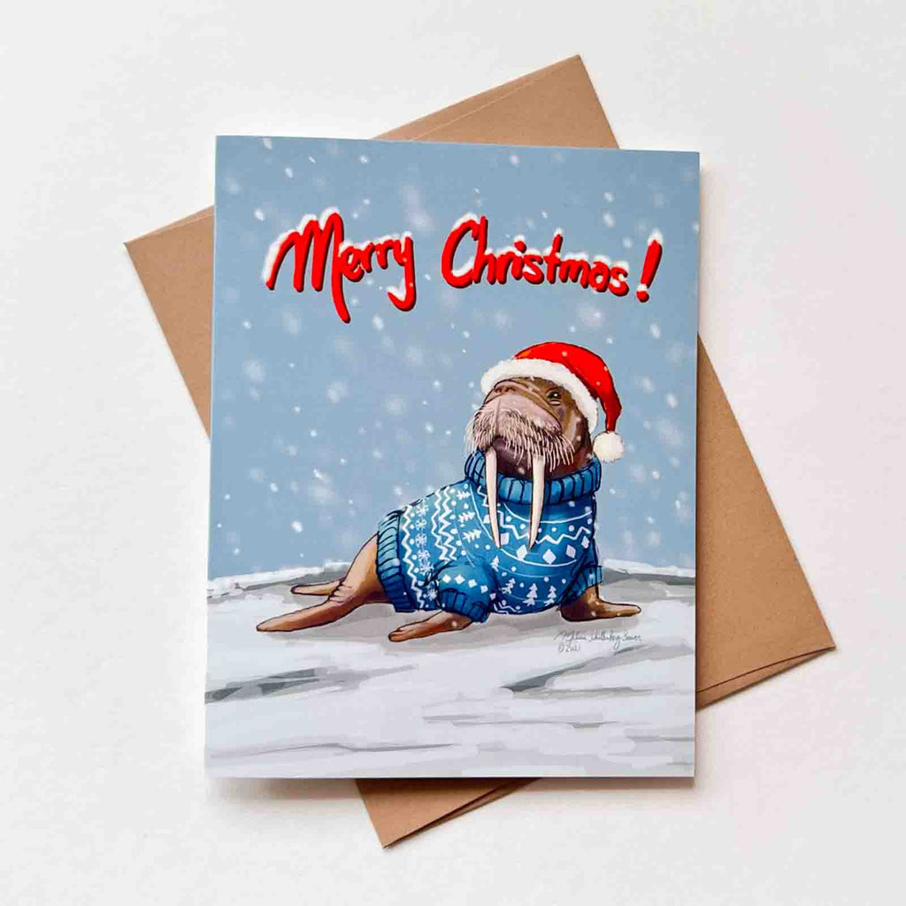 This holiday card features a walrus wearing a Christmas sweater in a snowy background