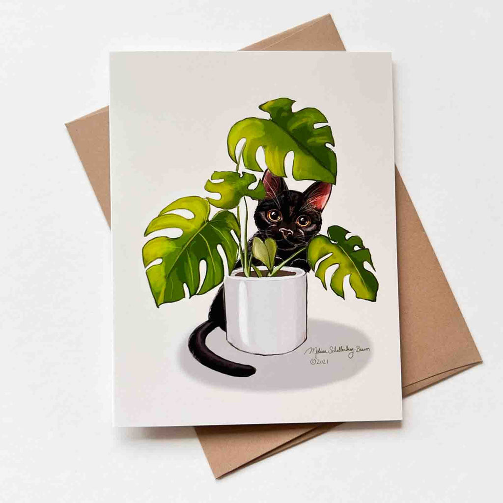 This blank notecard features a black cat peaking through a Monstera house plant