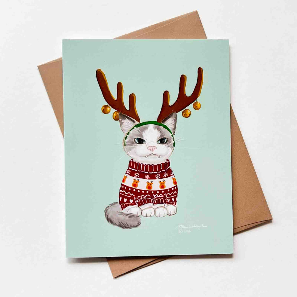 a funny christmas card featuring a grumpy cat who is wearing reindeer antlers and an ugly Christmas sweater