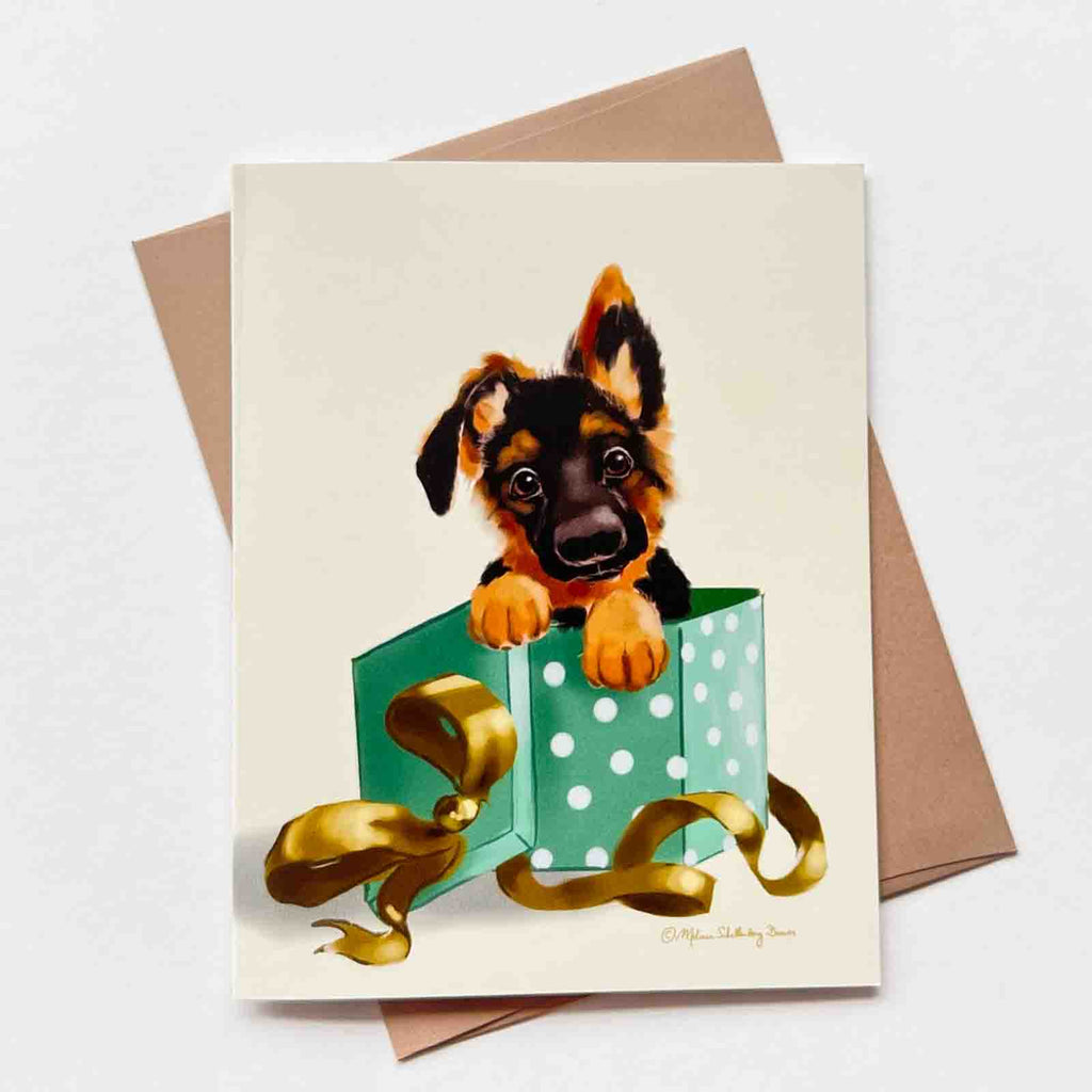 This versatile greeting card features an adorable German Shepherd Puppy dog popping out of a gift box. It can be used for Christmas, birthdays and more