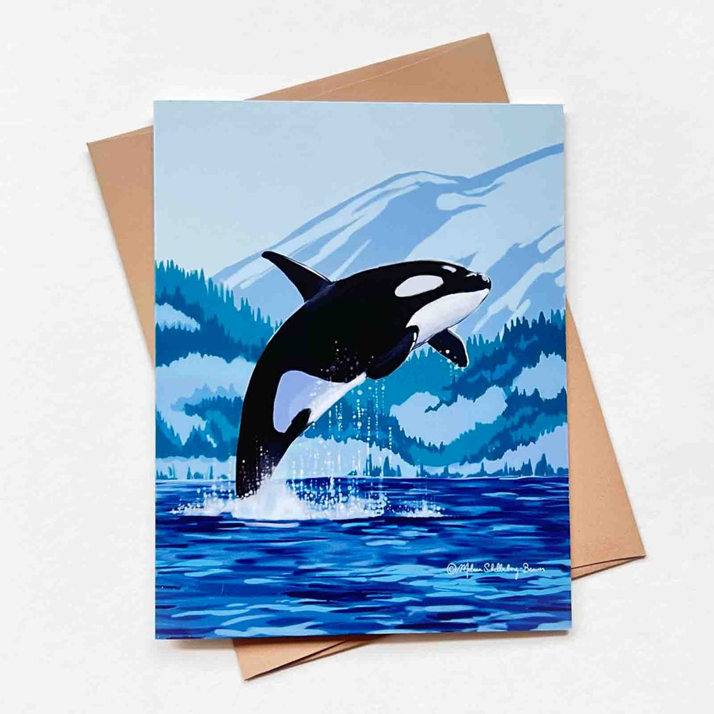 This greeting card features an Orca (aka Killer Whale) leaping out of the ocean against a backdrop fo mountains. 