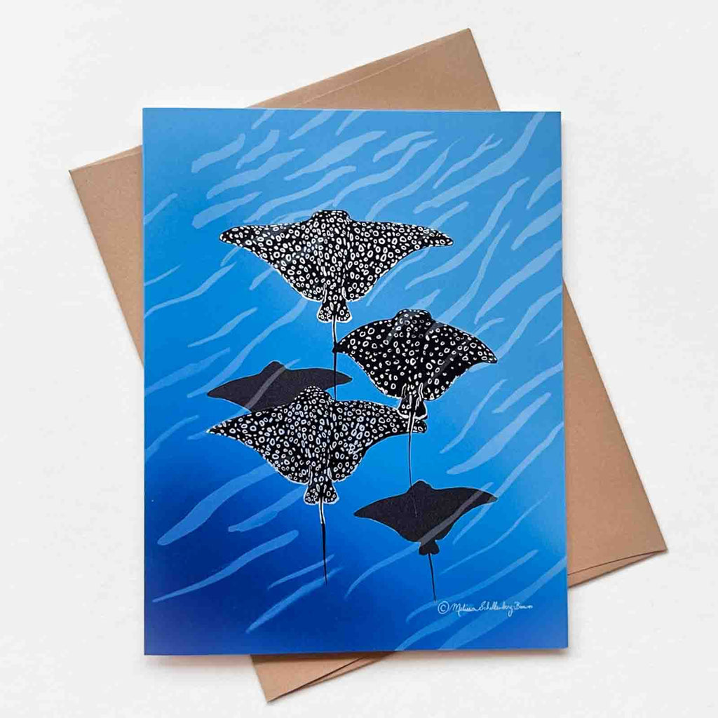 a greeting card featuring a schoo lof stingrays, specifically Spotted Eagle Rays swimming peacefully in the blue ocean