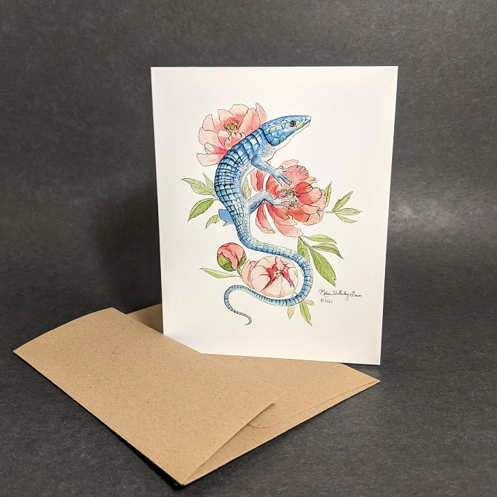 a notecard featuring a blue lizard resting on peony flowers