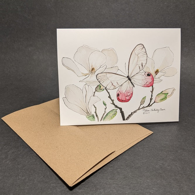 a beautiful notecard featuring a pink and white butterfly resting on magnolia flowers