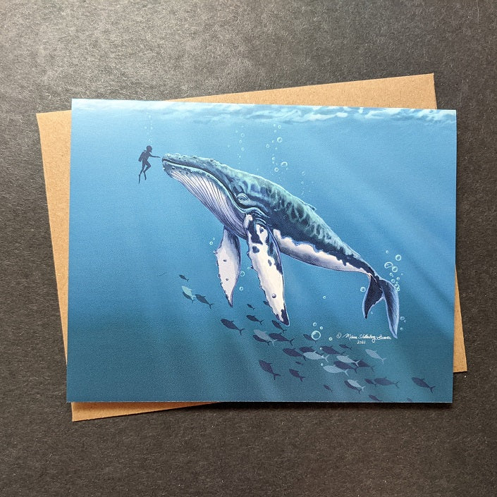 a notecard featuring a diver reaching out to touch an enormous humpback whale in the deep blue sea