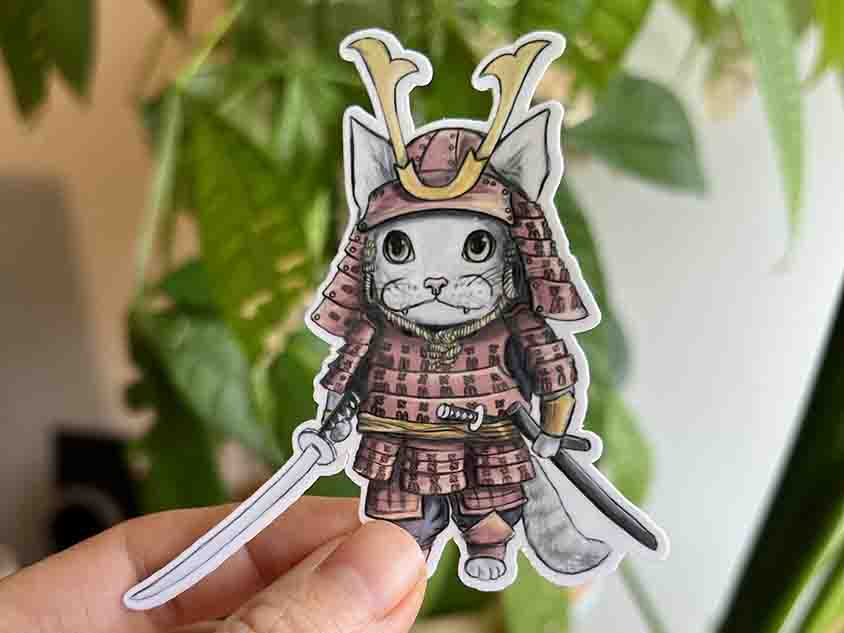 vinyl sticker featuring a stylized cat wearing Japanease Samurai warrior armour, holding a katana
